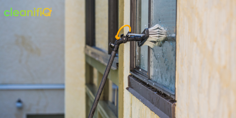 Professional cleaner using equipment to clean exterior windows of a tall building